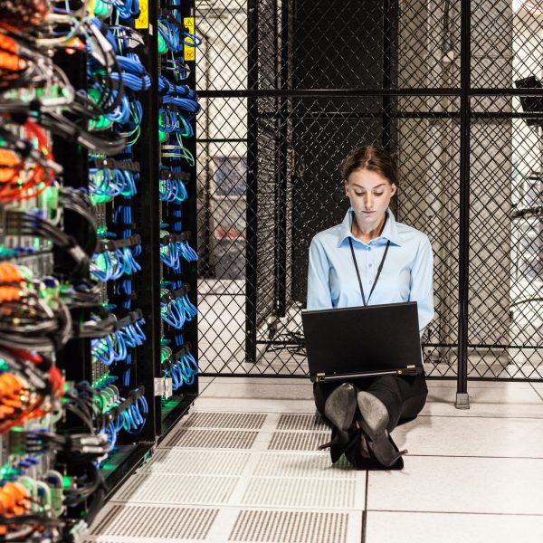 Caucasian woman technician working on computer servers in a server farm.