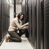 Caucasian woman technician working on computer servers in a server farm.