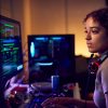 Female Teenage Hacker Sitting In Front Of Computer Screens Bypassing Cyber Security