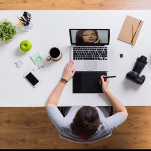 woman with camera working on laptop at table