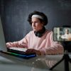 Young serious man in casualwear looking at computer screen while typing by desk